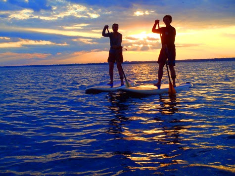 two people on SUP boards at sunset